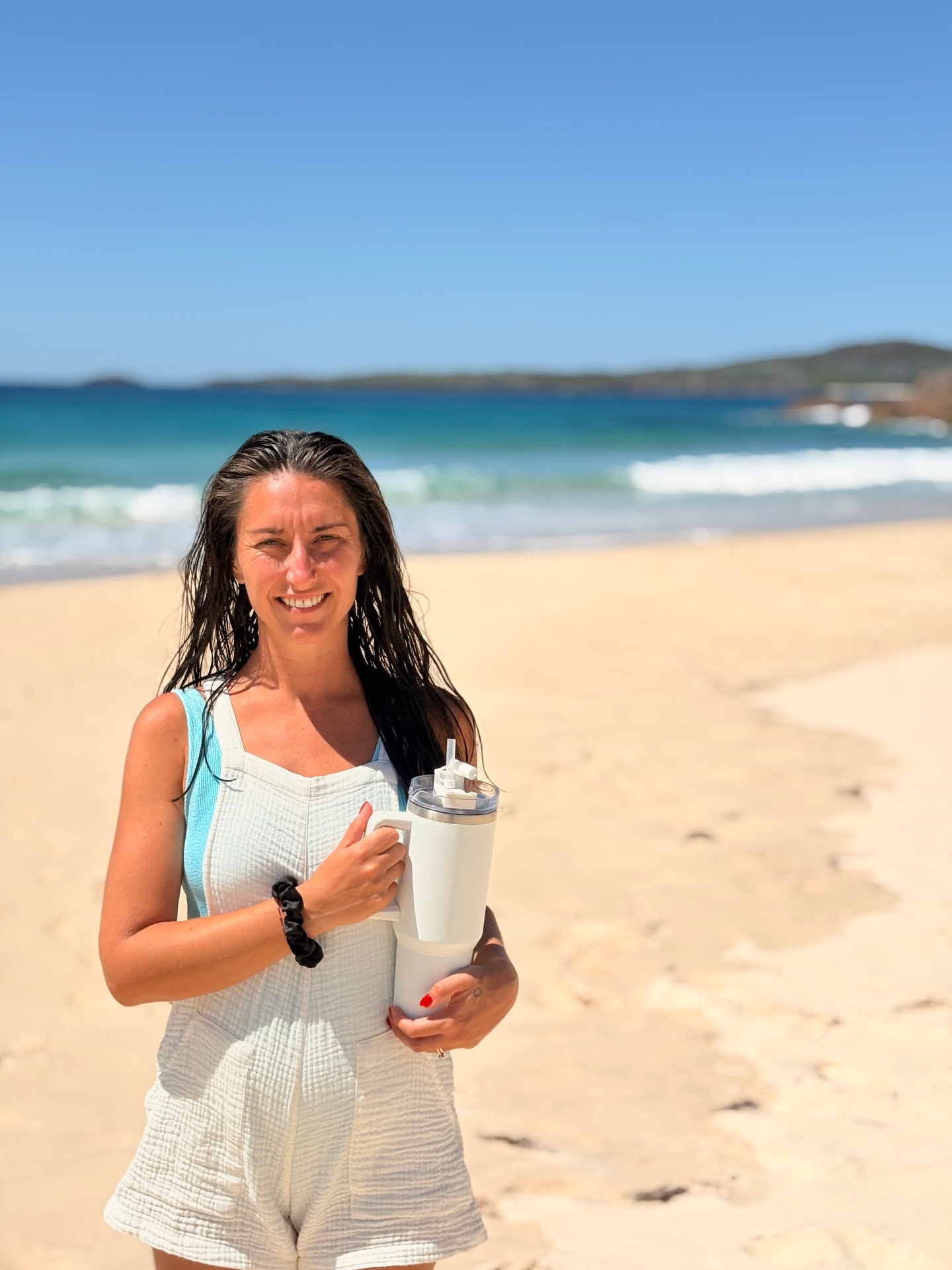 Portrait of Alyssa, founder of Frequency First, on the beach in cream linen